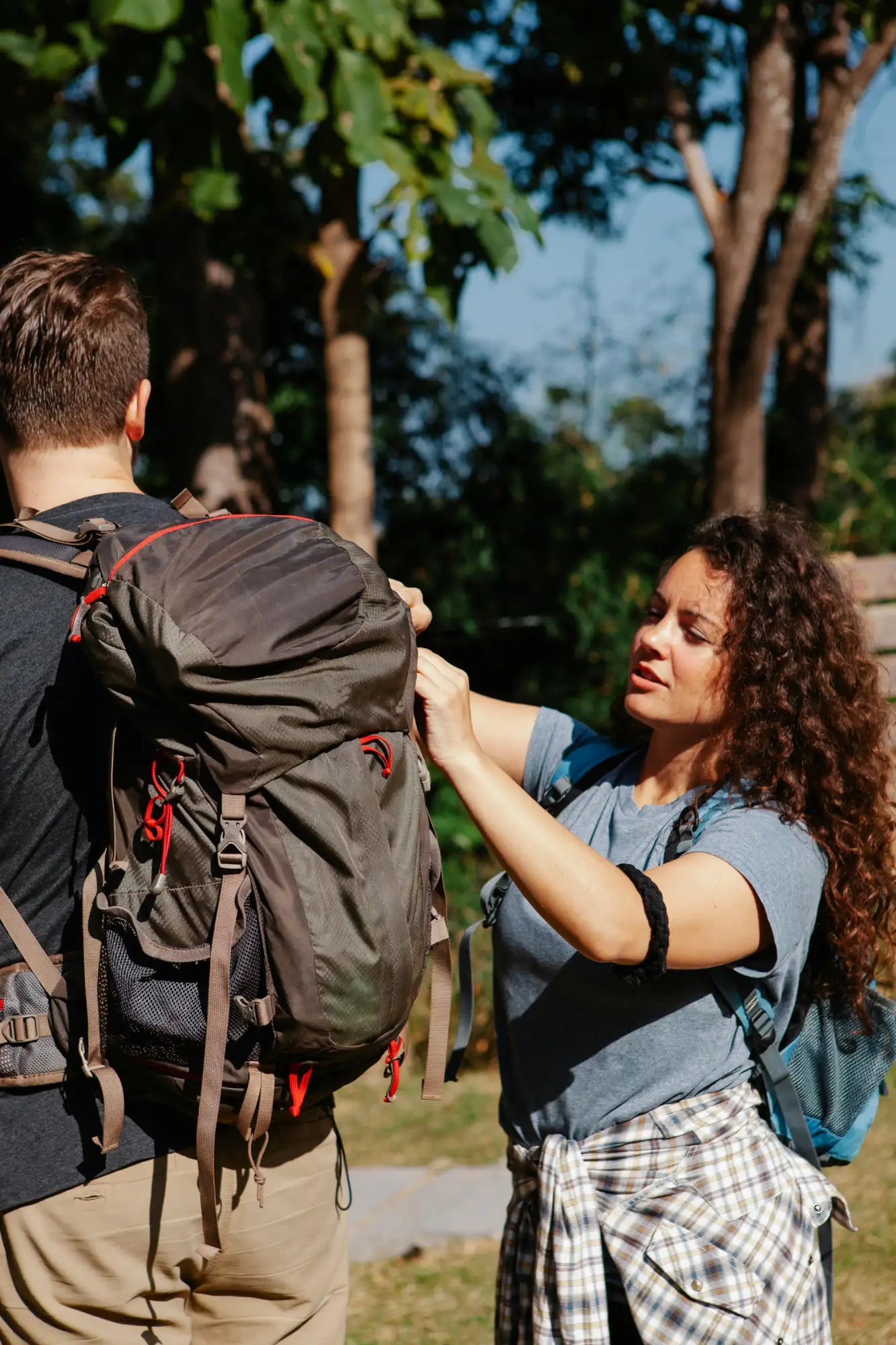 Sac à dos de randonnée vert olive foncé avec sangles d'accentuation rouges et sanglettes marron. Image